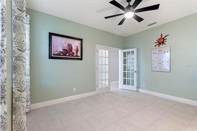 empty room with light tile patterned floors, a ceiling fan, visible vents, and baseboards