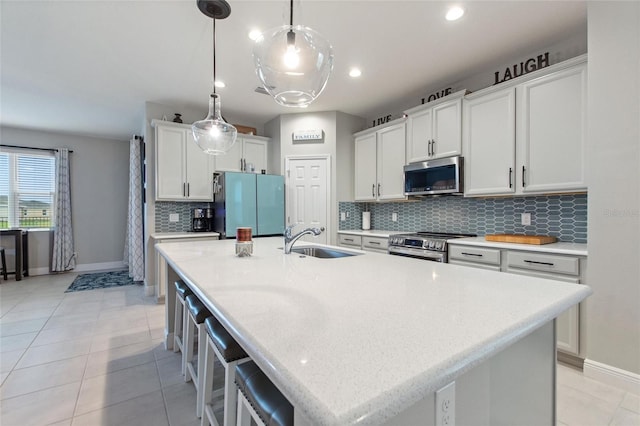 kitchen with light tile patterned flooring, appliances with stainless steel finishes, an island with sink, and a sink