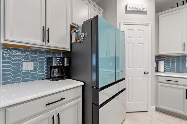 kitchen featuring light tile patterned floors, backsplash, light countertops, and freestanding refrigerator