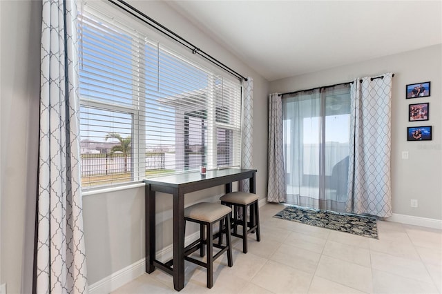 tiled dining space with plenty of natural light and baseboards