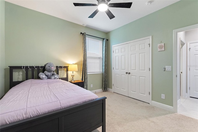 bedroom featuring a closet, light colored carpet, baseboards, and ceiling fan