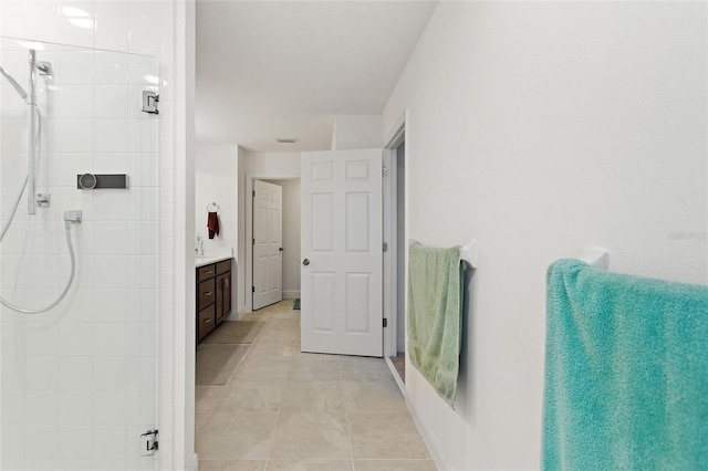 bathroom with vanity, tile patterned floors, baseboards, and a tile shower