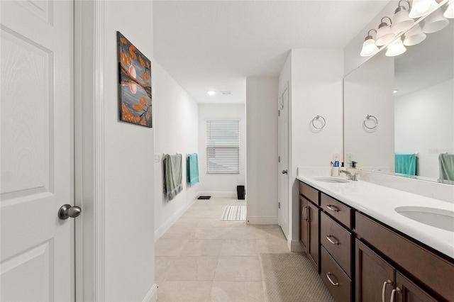 full bath featuring double vanity, tile patterned floors, baseboards, and a sink