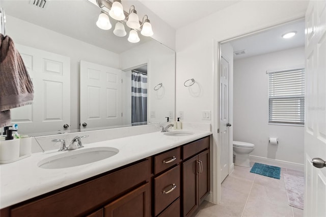 bathroom featuring tile patterned floors, visible vents, double vanity, and a sink