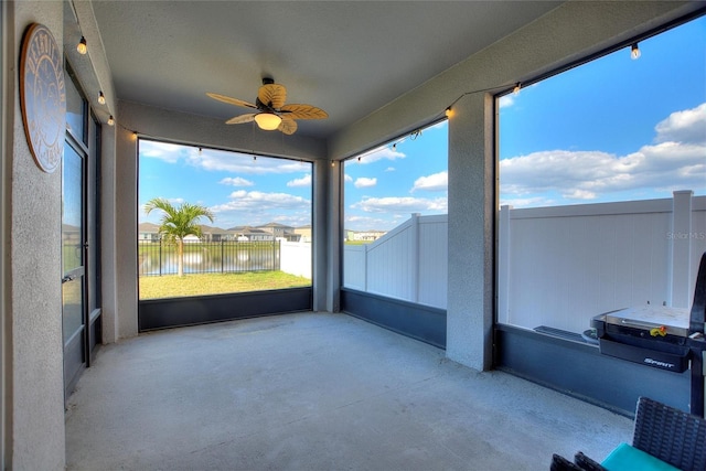 unfurnished sunroom with a ceiling fan and a water view