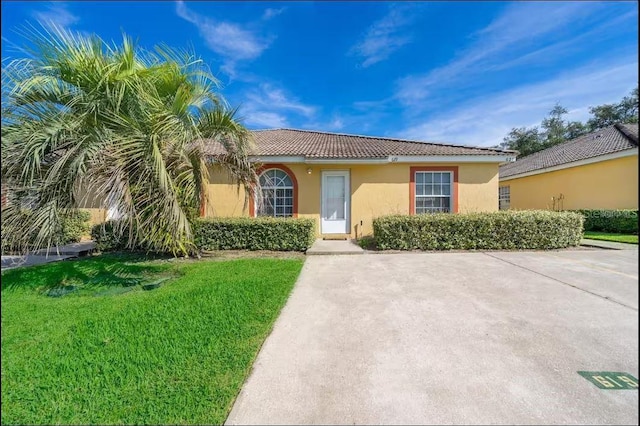 ranch-style house with stucco siding, a tiled roof, and a front yard