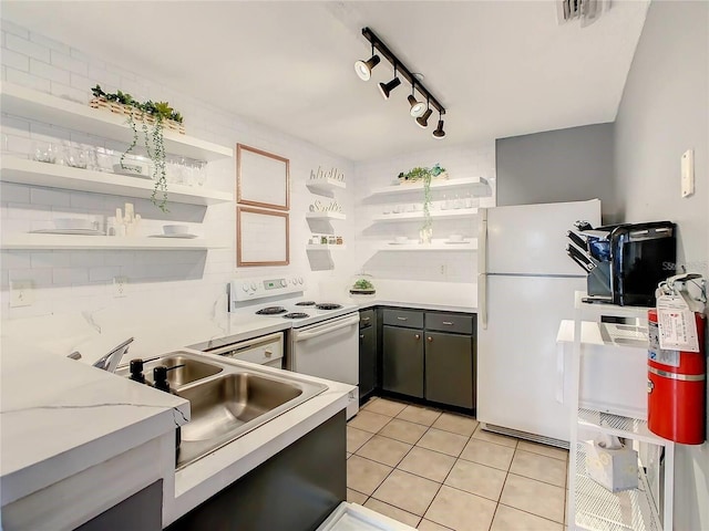 kitchen with white appliances, light tile patterned floors, open shelves, a sink, and light countertops