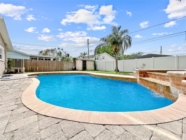 view of swimming pool featuring a fenced in pool, a shed, a patio area, a fenced backyard, and an outbuilding