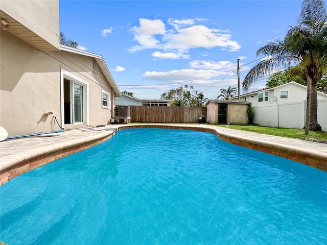 view of pool featuring an outbuilding, cooling unit, a fenced in pool, a fenced backyard, and a storage shed