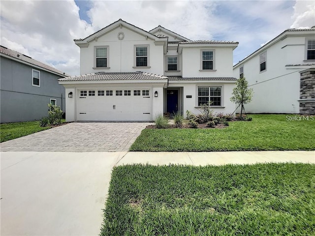 view of front of house featuring stucco siding, a front lawn, decorative driveway, an attached garage, and a tiled roof