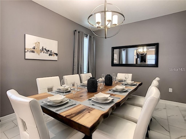 dining room featuring an inviting chandelier, baseboards, and marble finish floor