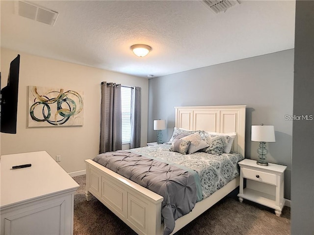 bedroom with visible vents, baseboards, a textured ceiling, and dark carpet