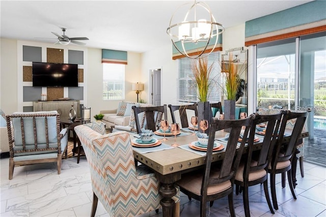 dining room with ceiling fan with notable chandelier and marble finish floor