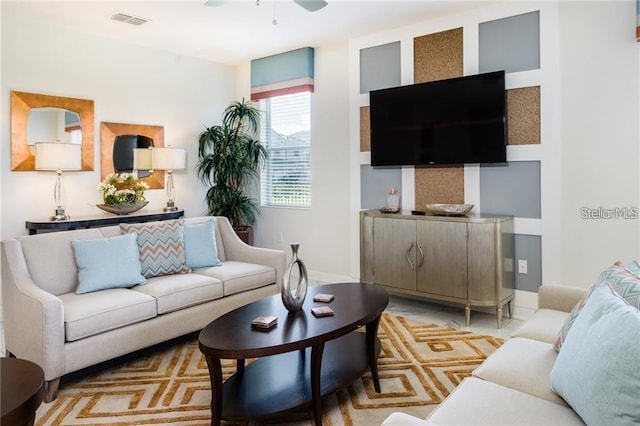 living area with baseboards, visible vents, and ceiling fan