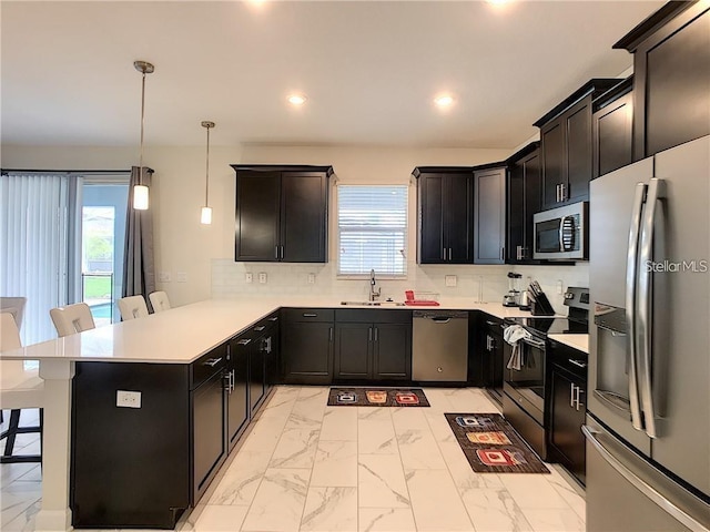 kitchen with backsplash, a kitchen bar, appliances with stainless steel finishes, marble finish floor, and a sink