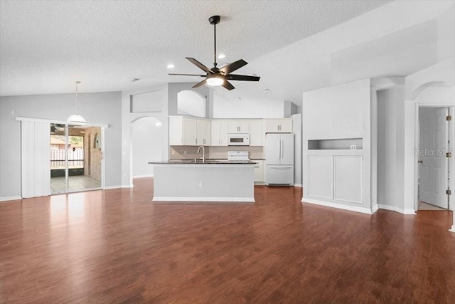 unfurnished living room with a ceiling fan, dark wood finished floors, arched walkways, a sink, and a textured ceiling