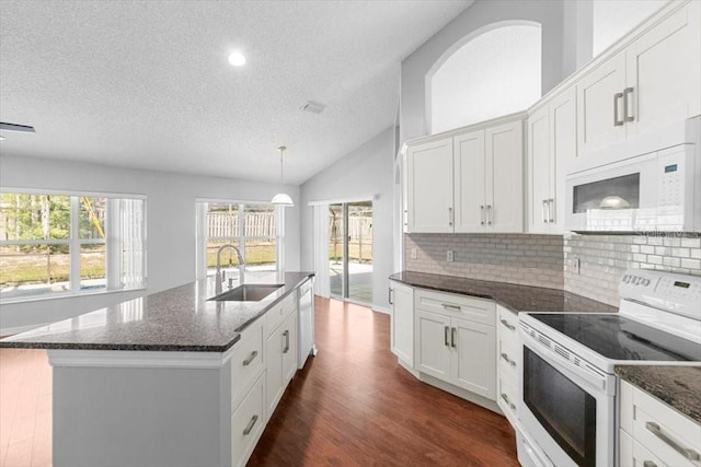 kitchen with a sink, vaulted ceiling, decorative backsplash, white appliances, and dark wood-style flooring