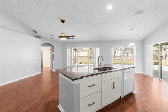 kitchen with a center island with sink, vaulted ceiling, white dishwasher, arched walkways, and a sink