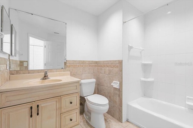 bathroom with vanity, wainscoting, tile walls, toilet, and tile patterned floors