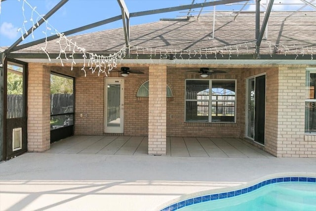 rear view of property featuring a patio, brick siding, a lanai, and a shingled roof