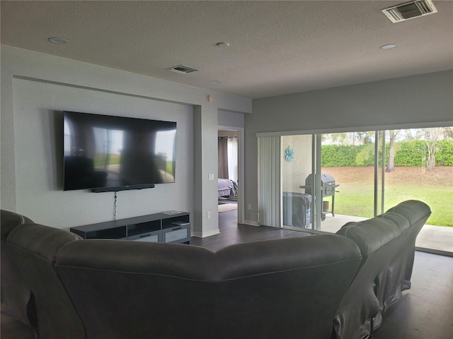 living room with visible vents, a textured ceiling, and wood finished floors