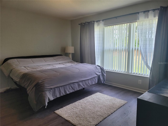 bedroom with baseboards, multiple windows, and wood finished floors