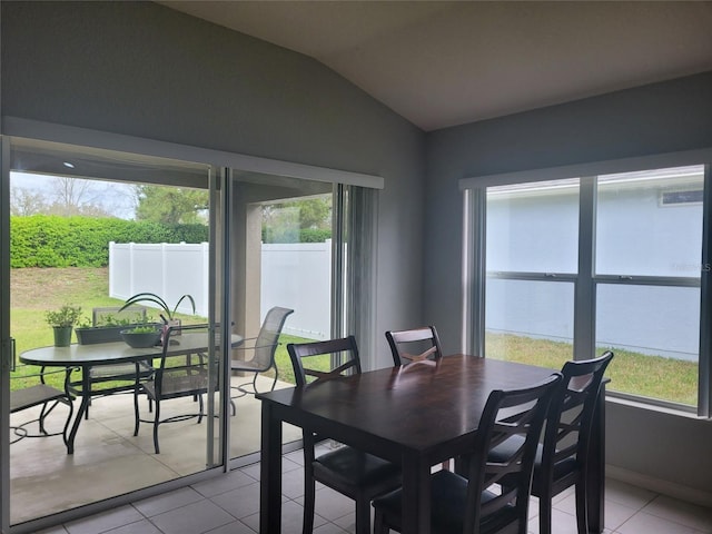 dining room with baseboards, lofted ceiling, light tile patterned floors, and plenty of natural light