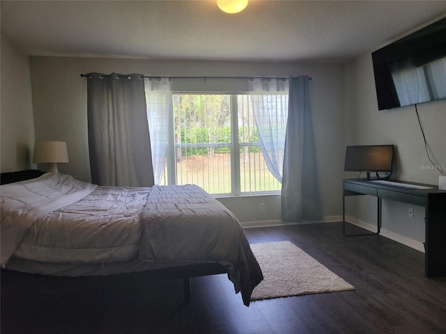 bedroom featuring baseboards, a textured ceiling, and wood finished floors