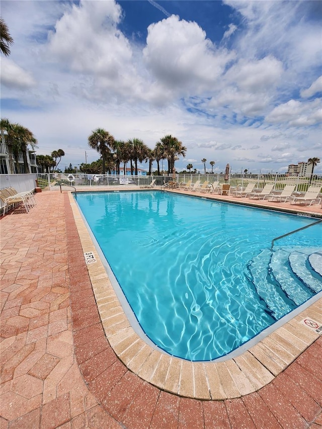 community pool with a patio and fence