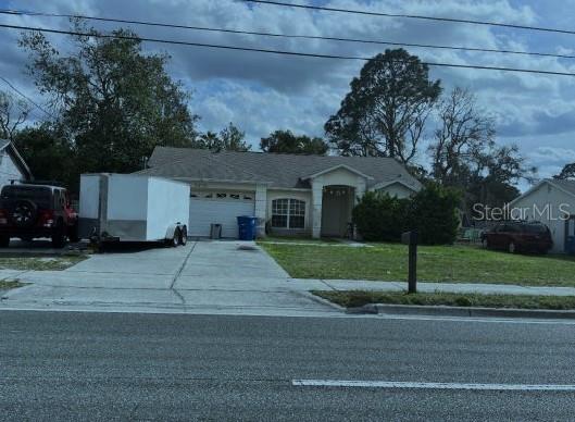 view of front of property featuring a garage, a front lawn, and driveway