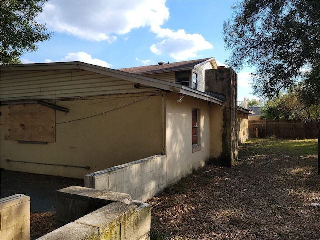 view of side of home with fence and stucco siding