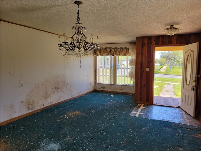 unfurnished dining area with a chandelier, a healthy amount of sunlight, a textured ceiling, and carpet