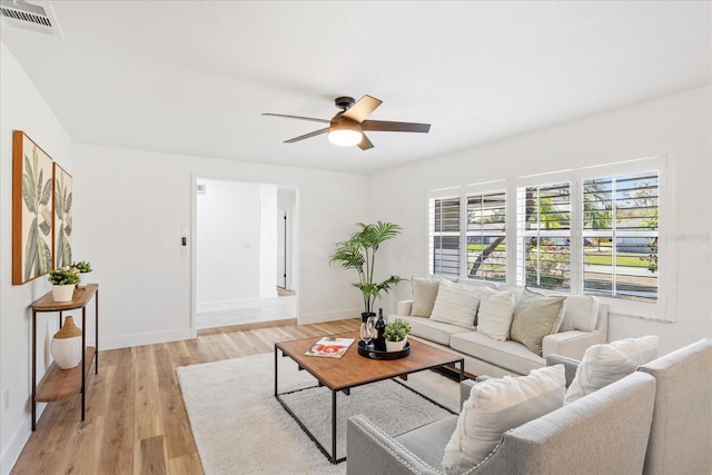 living area featuring visible vents, baseboards, a ceiling fan, and light wood finished floors