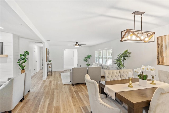 dining space featuring light wood-style flooring, a ceiling fan, and baseboards