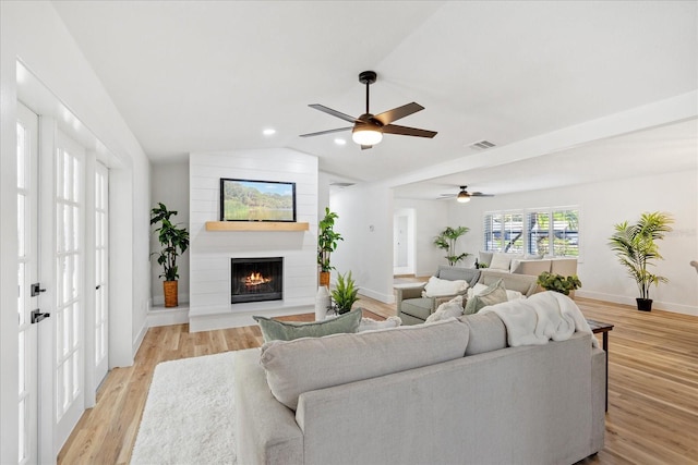 living room featuring visible vents, light wood-style flooring, lofted ceiling, and ceiling fan