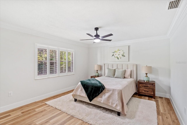 bedroom with visible vents, ceiling fan, baseboards, ornamental molding, and light wood-style floors