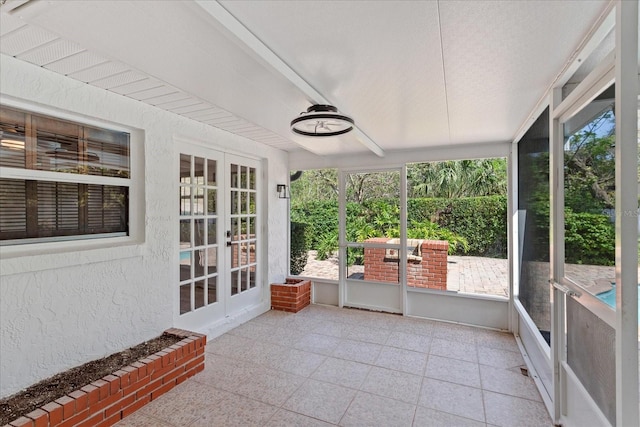 sunroom featuring beam ceiling and french doors