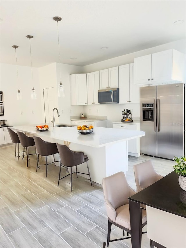 kitchen with white cabinetry, a kitchen bar, appliances with stainless steel finishes, and a sink