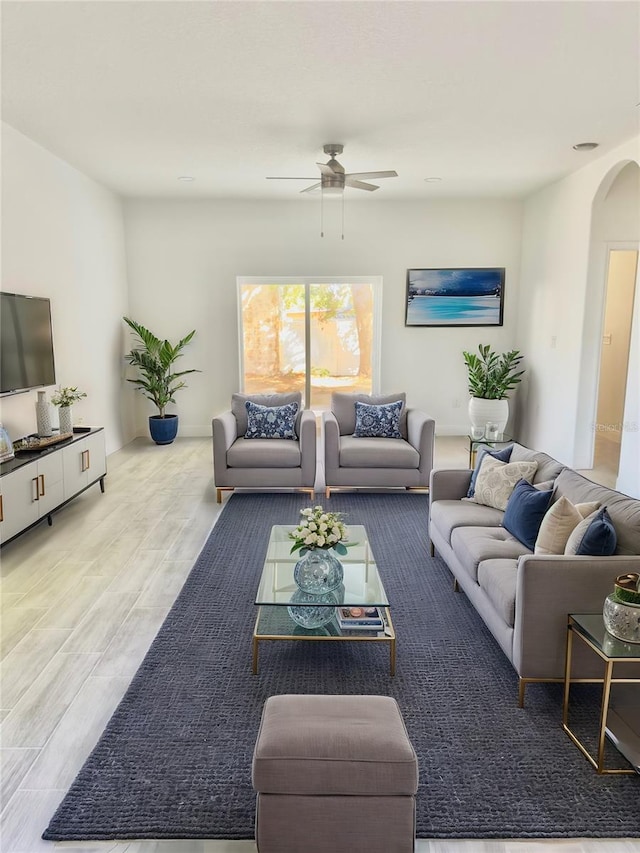 living room with wood finished floors, arched walkways, and ceiling fan