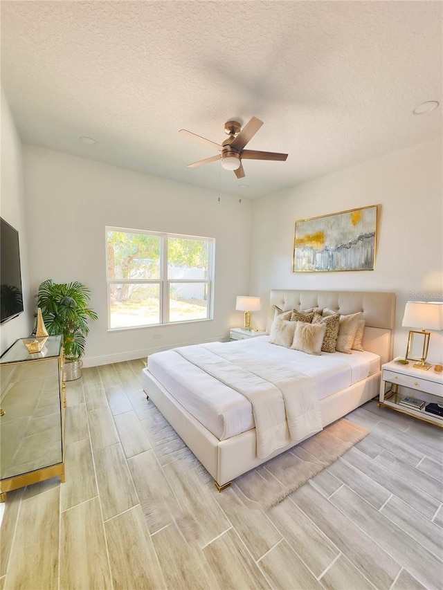 bedroom with baseboards, a textured ceiling, ceiling fan, and wood tiled floor