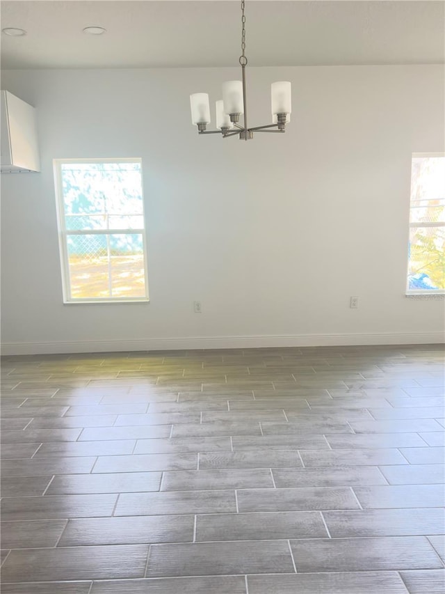 spare room with wood tiled floor, baseboards, and a chandelier