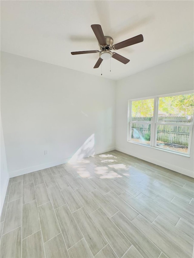 unfurnished room featuring wood tiled floor, baseboards, and ceiling fan