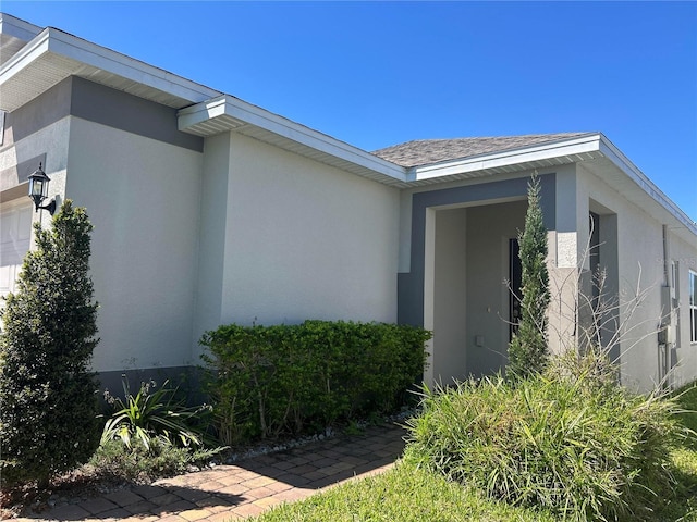 property entrance with stucco siding and an attached garage