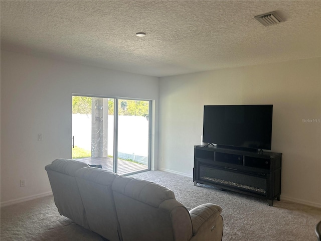 carpeted living area with visible vents, a textured ceiling, and baseboards