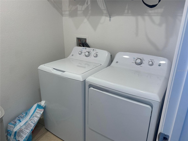 laundry area featuring light tile patterned floors, laundry area, washing machine and dryer, and a textured wall