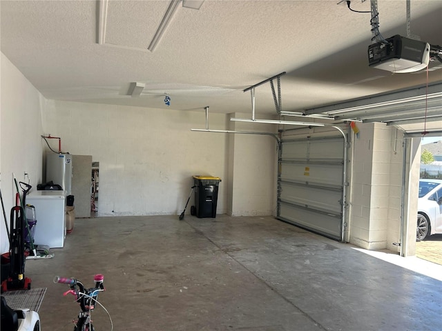 garage featuring water heater, concrete block wall, washer / clothes dryer, and a garage door opener