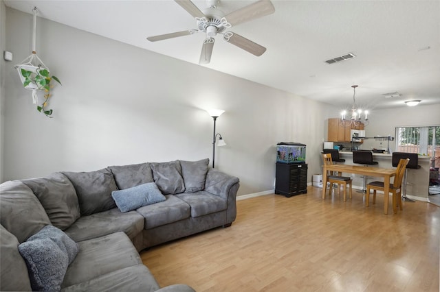 living area featuring visible vents, baseboards, light wood-style floors, and ceiling fan with notable chandelier