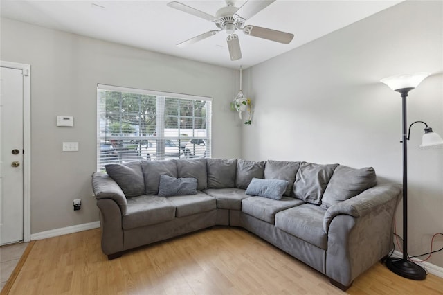 living area with baseboards, light wood-style flooring, and a ceiling fan