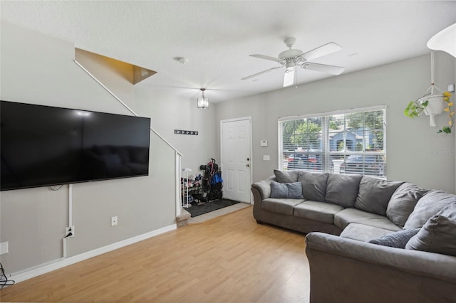 living room featuring baseboards, a ceiling fan, and light wood-style floors