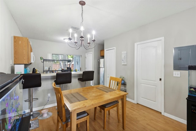 dining area featuring electric panel, baseboards, a notable chandelier, and light wood finished floors